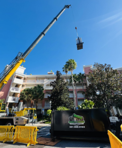 A Dump N Gone dumpster placed at a construction site with a crane operating in the background in Apopka, FL.