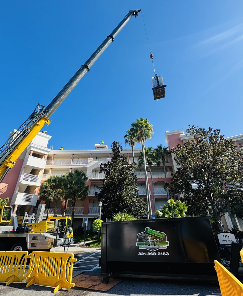 A Dump N Gone dumpster placed at a construction site with a crane operating in the background in Apopka, FL.
