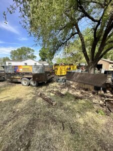 A WeHaul Hauling & Junk Removal dump trailer and a large yellow dumpster at a junk removal site in Sioux Falls, SD.