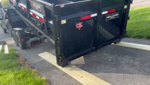 A dump trailer being carefully lowered onto wooden planks for a junk removal job by Junk Lockdown LLC in Lancaster, PA.