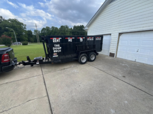 A black dump trailer from The Dump Bros LLC hooked to a truck in a residential driveway in Raleigh, NC.