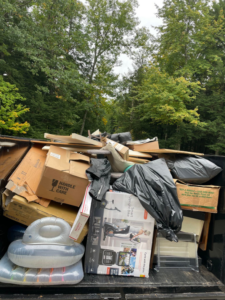 A dump trailer overflowing with various household junk items, boxes, and debris for removal by Averson Hauling & Disposal LLC in Lebanon, ME