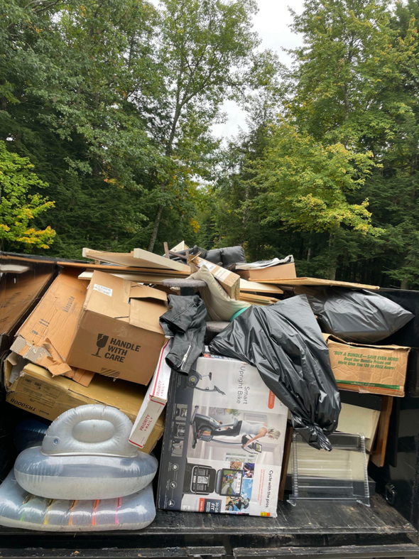 A dump trailer overflowing with various household junk items, boxes, and debris for removal by Averson Hauling & Disposal LLC in Lebanon, ME