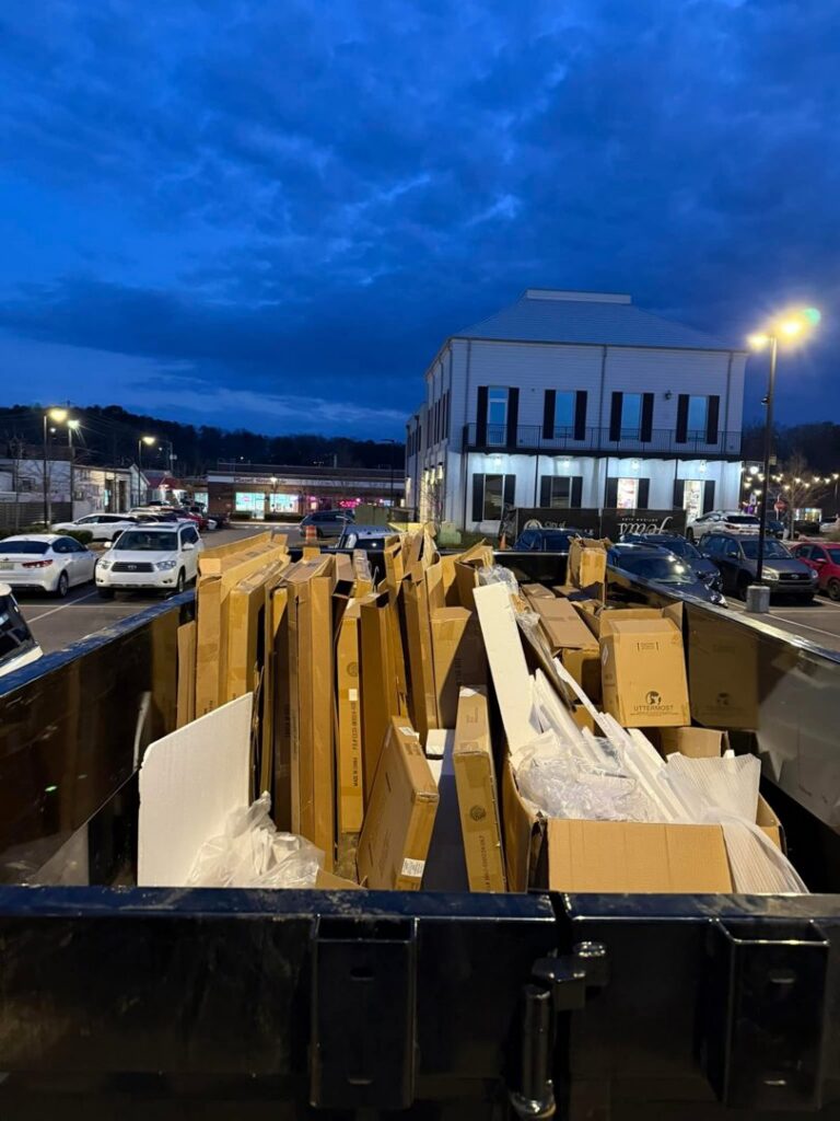 A Marc & Park Junk Removal, LLC dump trailer filled with cardboard boxes and debris in Birmingham, AL.