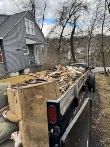 A dump trailer filled with household junk, including a couch and wood debris, by Trash & Dash in Houston, TX.