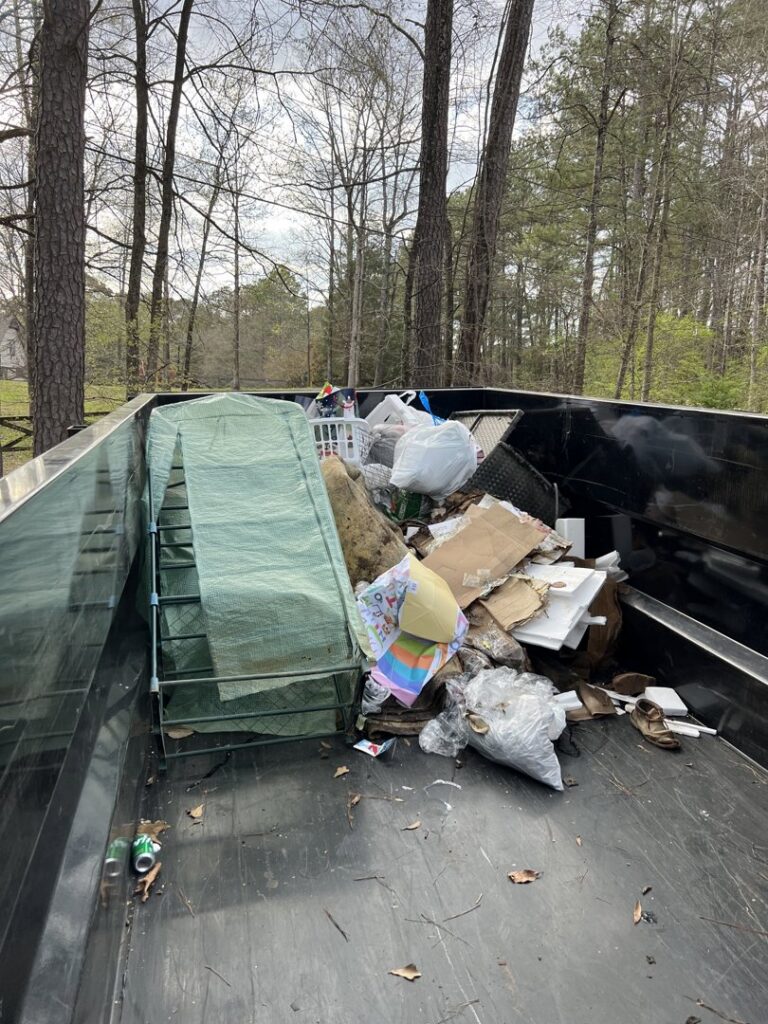 A Marc & Park Junk Removal, LLC dump trailer filled with household junk, including a mattress and boxes, in Birmingham, AL.