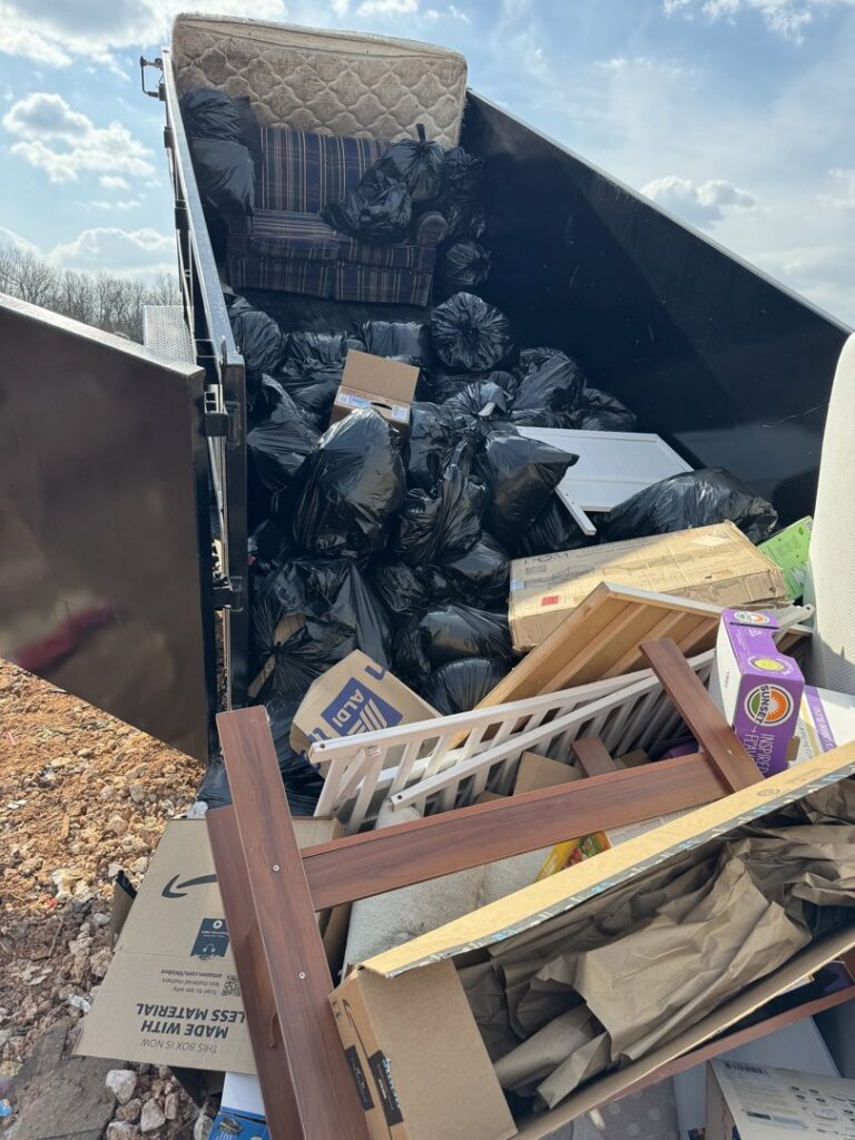 A dump trailer completely full of household junk, including a mattress and trash bags, by Waste Walkers Dispatch in Springfield, MO.