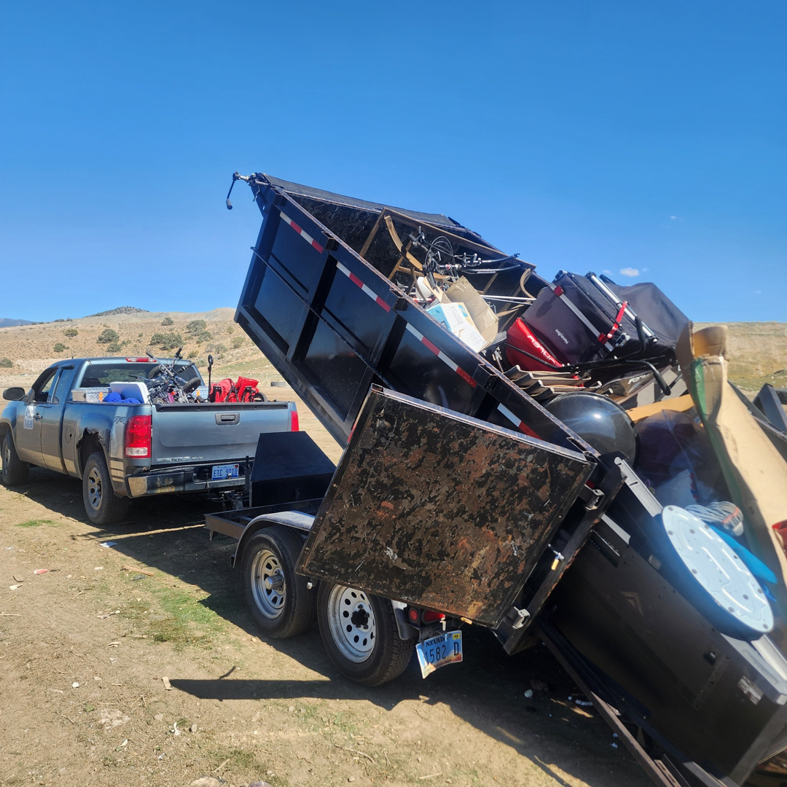 A dump trailer full of various junk items being unloaded by Dunk The Junk in Carson City, NV.