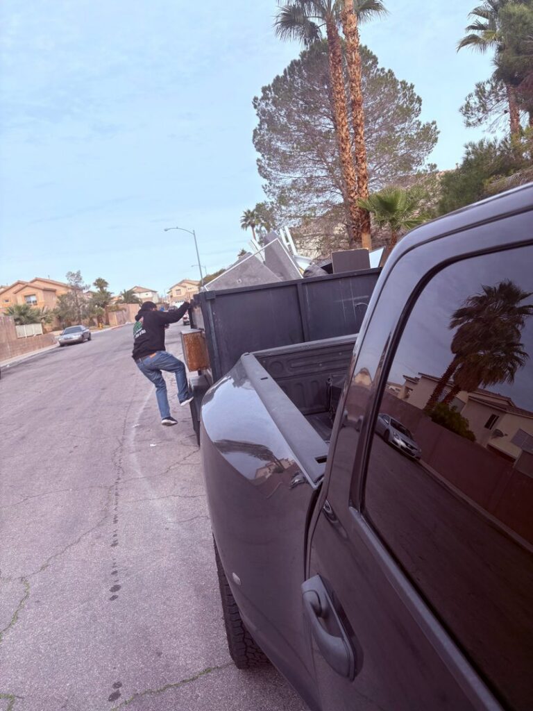 A dump trailer filled with a variety of junk, including old furniture and trash bags, after a successful junk removal by Mike's Dumper in Las Vegas, NV.