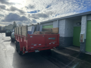 A red dump trailer filled with mattresses and debris, ready for hauling by Sinclair Waste Removal & Hauling LLC in St. Charles, MO.