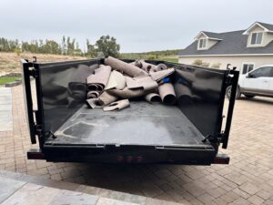 A dump trailer filled with rolled-up old carpets, ready for disposal by Haul My Load LLC in Caldwell, ID.