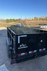 A dump trailer filled with tree branches and yard waste, being hauled away by Haul My Load LLC in Caldwell, ID.