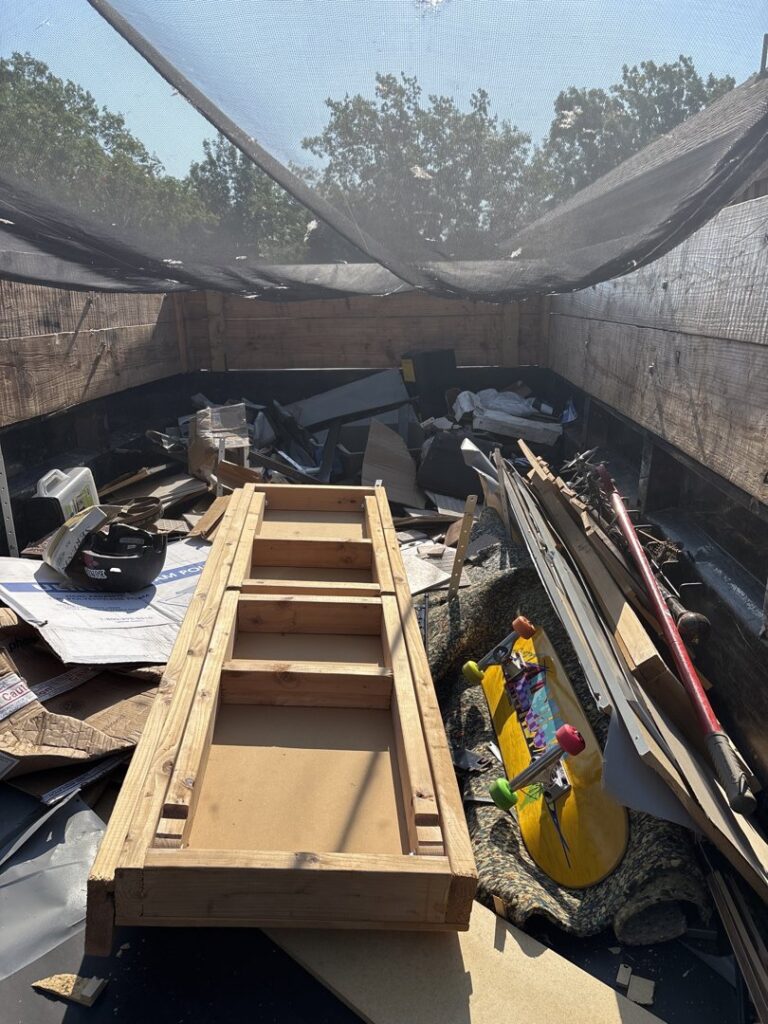 A Grawe Junk & Demo dump trailer filled with various junk items, including wood and cardboard, ready for removal in Arlington, TX.