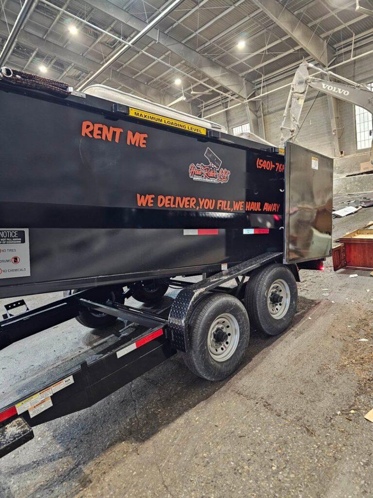 A black dump trailer from Haul Rollers LLC parked inside a transfer station, ready for junk disposal in Roanoke, VA.