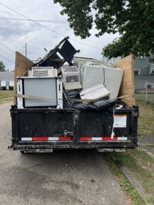 A dump trailer filled with old appliances and various junk, ready for disposal by Sos Junk Removal in Akron, OH.