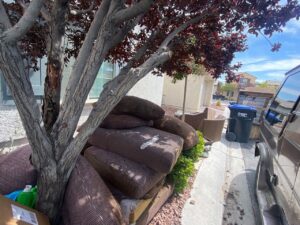A dump trailer fully loaded with old furniture, tires, and various household junk, ready for transport by Mike's Dumper in Las Vegas, NV.