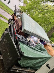A dump trailer filled with a mattress, furniture, and bags of trash, handled by Sos Junk Removal in Akron, OH.