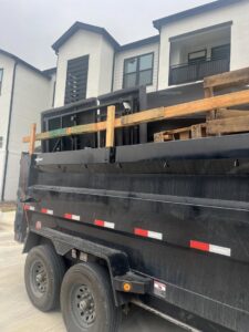 A dump trailer loaded with wooden pallets and construction debris, handled by Silverhull Junk Removal in San Antonio, TX