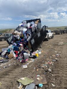 A dump trailer overflowing with various household junk being unloaded, demonstrating junk removal by Outlaw Rental in Bismarck, ND.