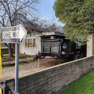 A Valley Haul Off LLC dump trailer parked in front of a residential property, ready for a junk removal job in Visalia, CA.