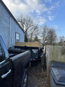 A dump trailer with wooden extensions parked next to a house for junk removal services by Salt Creek Disposal in Bowling Green, KY.