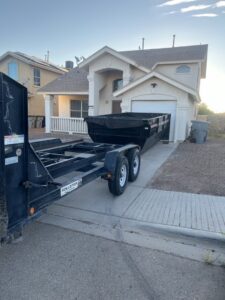 An empty dump trailer being placed in a residential driveway for junk removal by Construction Removal Services Inc. in El Paso, TX.
