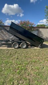 A black dump trailer with its bed raised, ready for loading or unloading by JB'S Junk Removal in Justin, TX.