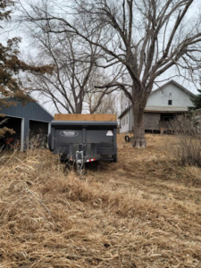 An empty dump trailer parked on a rural property, ready for cleanout services from Big O Dumpster in Omaha, NE.