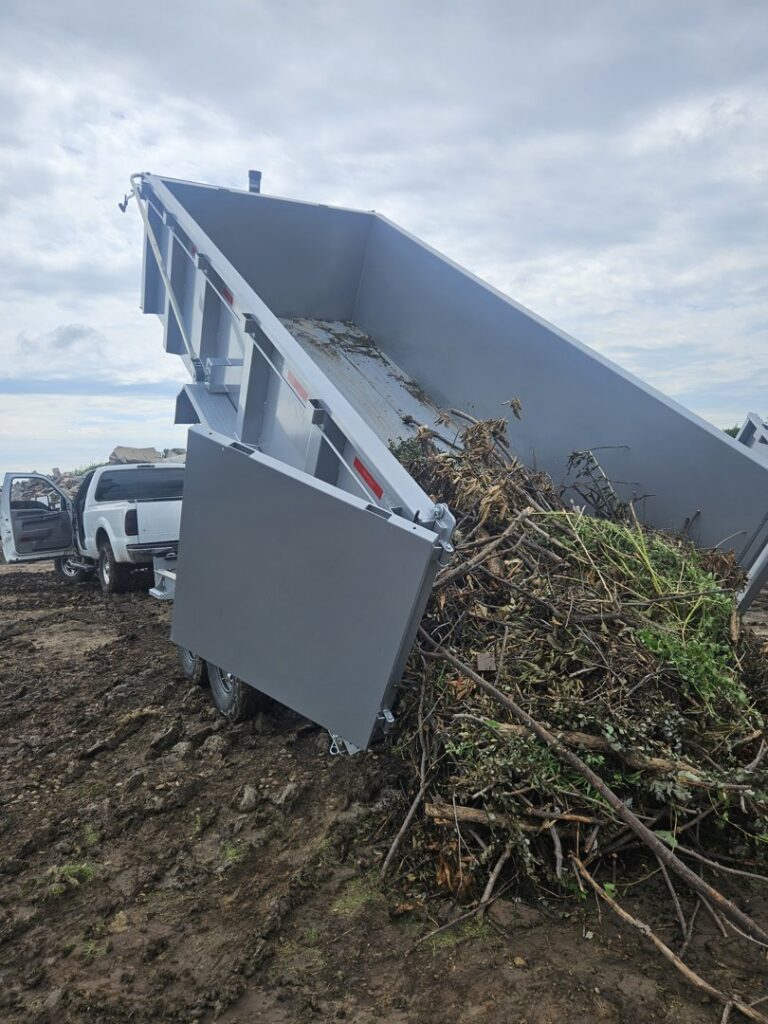 A dump trailer from Alpha Outdoor Services LLC disposing of tree branches and green waste in Kearney, NE.