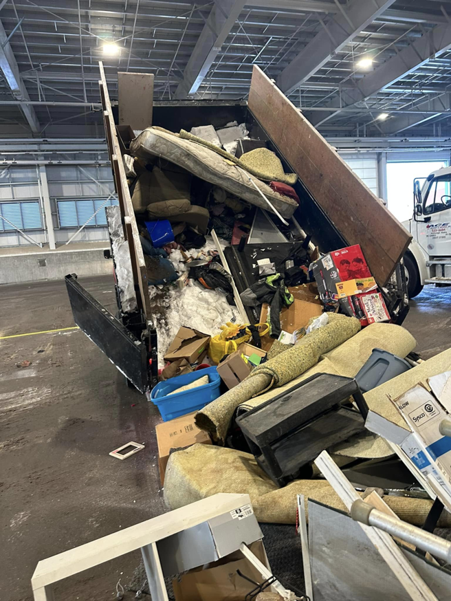 A dump trailer unloading bulky junk like mattresses and carpets at a facility for Haul-Away in Anchorage, AK.