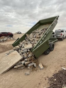 A green dump trailer from Easy Load Disposal El Paso unloading concrete debris at a disposal site in El Paso, TX.