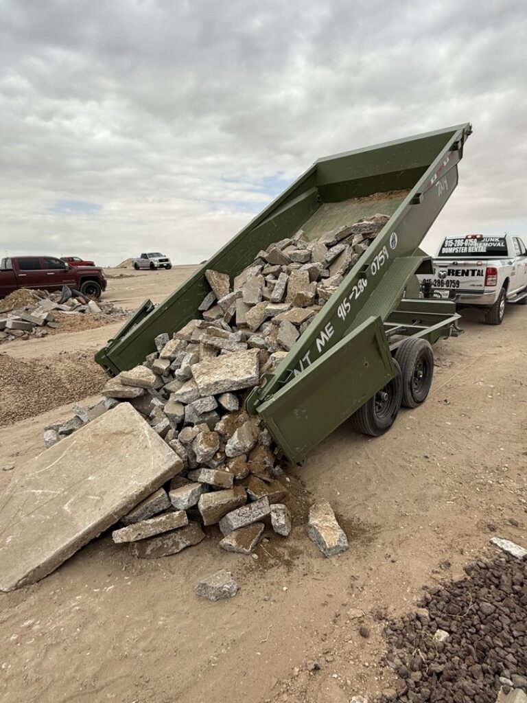 A green dump trailer from Easy Load Disposal El Paso unloading concrete debris at a disposal site in El Paso, TX.
