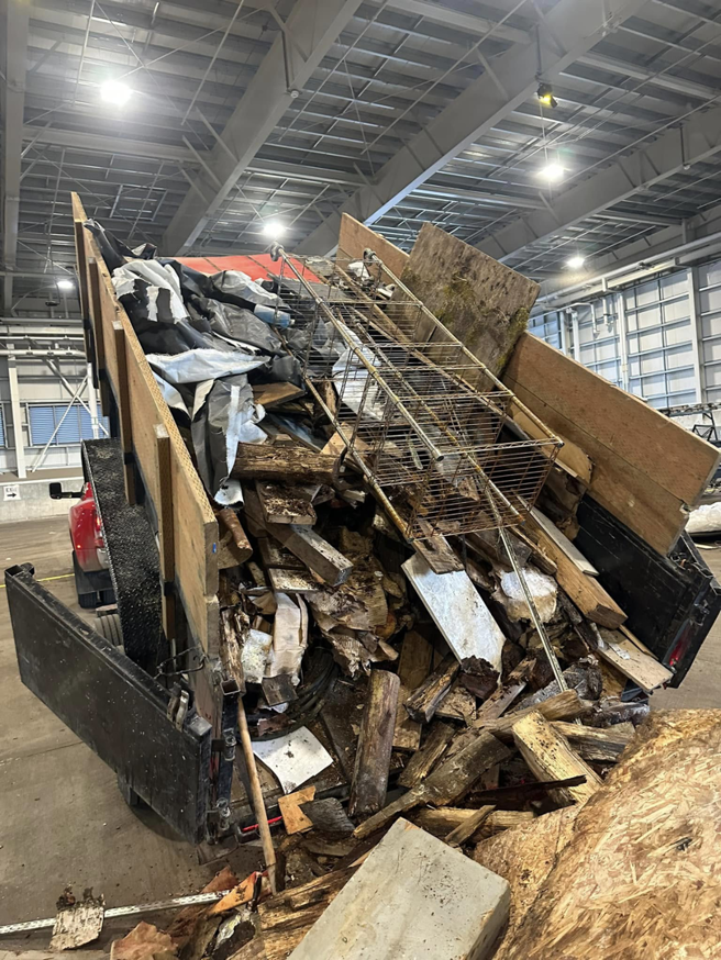 A dump trailer filled with wood, metal, and various debris being unloaded by Haul-Away in Anchorage, AK.