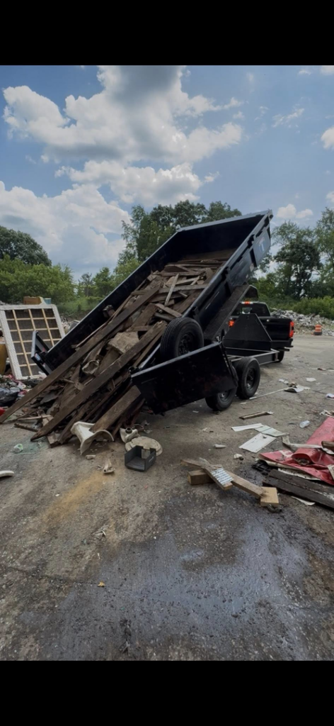A dump trailer actively unloading a large pile of wooden debris and other junk, demonstrating disposal services by Speedy Scrap Junk Removal LLC in Portage, WI.