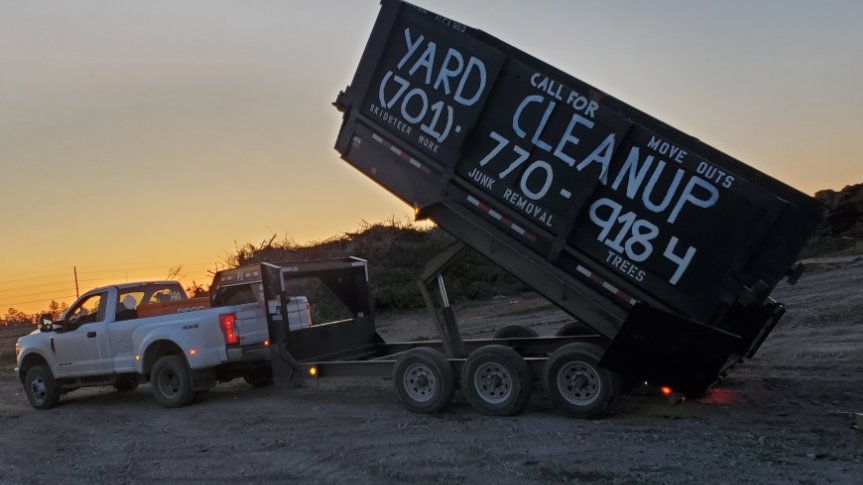 A dump trailer unloading junk and debris at sunset, showcasing services by 701 Scrap in Williston, ND.