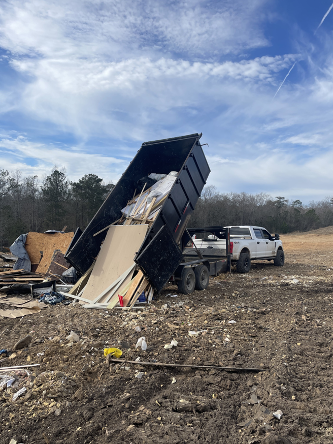 A dump trailer unloading construction debris and junk at a job site for Merritt Hauling and Disposal in Columbus, GA.