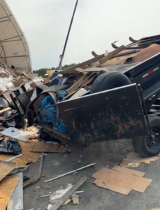 A dump trailer actively unloading a large volume of mixed junk and debris at a disposal site, handled by Speedy Scrap Junk Removal LLC in Portage, WI.
