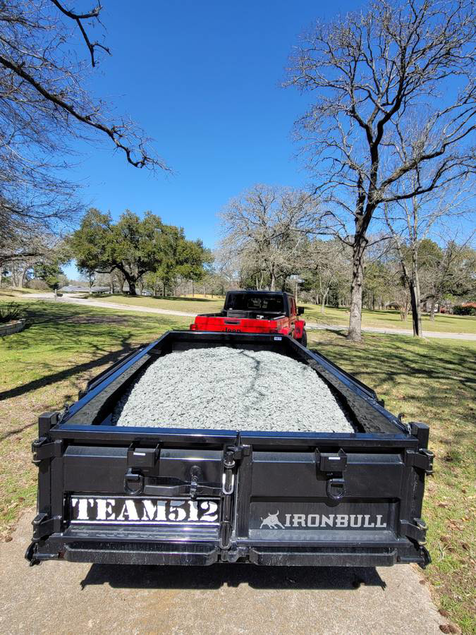 A black dump trailer filled with gravel, ready for a construction project by Team512 in Austin, TX