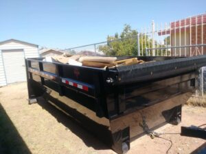 A dump trailer containing wood and other debris in a backyard, ready for removal by Construction Removal Services Inc. in El Paso, TX.
