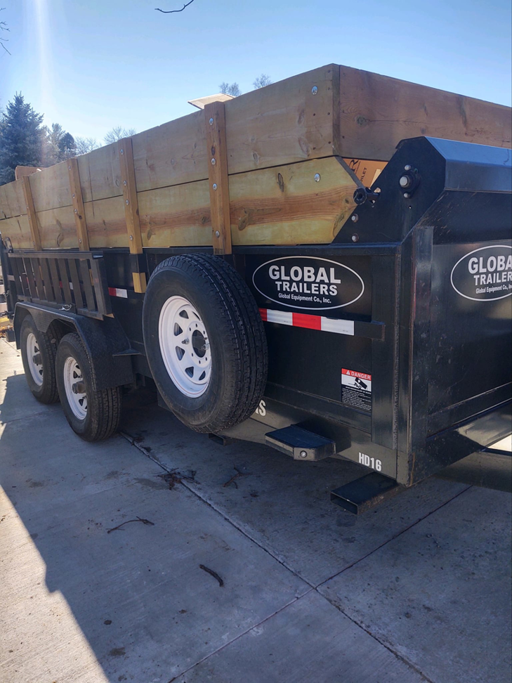 A black dump trailer with wooden side extensions, ready for junk removal services from Big O Dumpster in Omaha, NE.