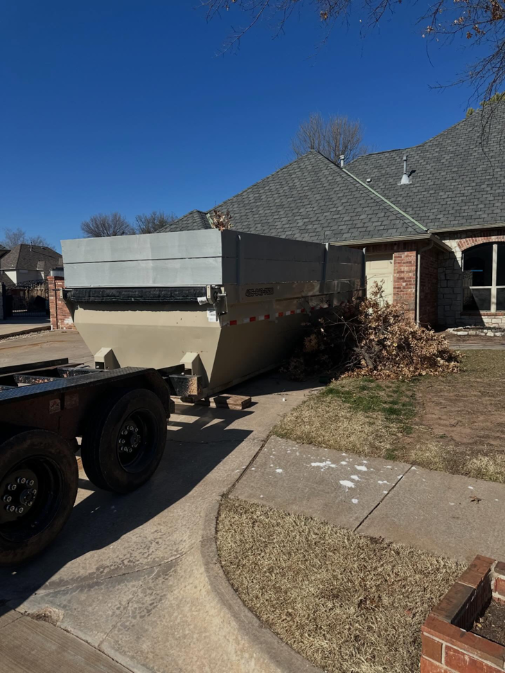 A dump trailer from Ricky's Dump Truck with yard waste and branches at a residential house in Oklahoma City, OK.