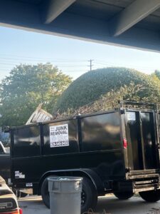 A New Haul Junk Removal dump trailer loaded with yard debris and wood for removal in Los Angeles, CA.