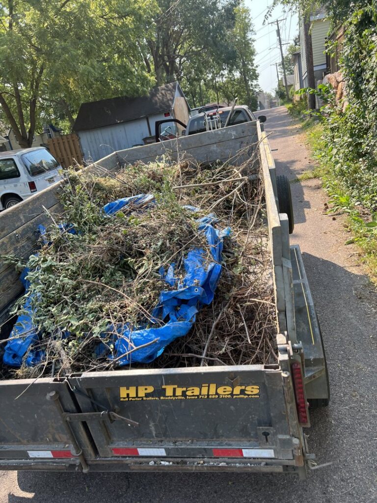 A dump trailer filled with yard waste and branches, ready for removal by WeHaul Hauling & Junk Removal in Sioux Falls, SD.