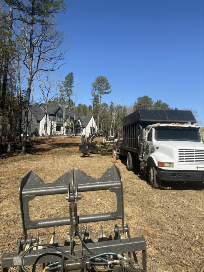 A dump truck and excavator clearing land after tree removal by MacNeela's Tree Service in Durham, NC