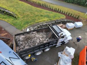 An ADE Hauling dump truck filled with roofing debris at a construction site in Tacoma, WA