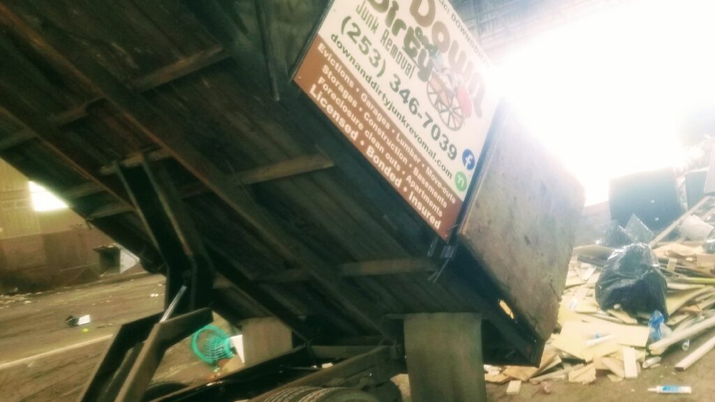 A Down and Dirty Junk Removal dump truck, with its bed tilted, full of debris at a job site in Tacoma, WA.