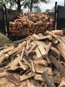 A dump truck filled with freshly cut firewood and logs, representing the output of tree services by Schnell Tree Services LLC in Fayetteville, NC.