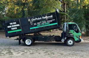 A green dump truck with the OnPoint Removal Services logo and raised bed, ready for junk removal in Vancouver, WA.