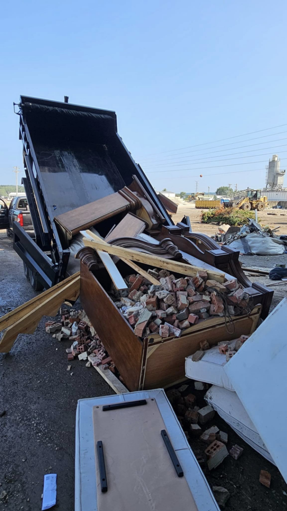 A dump truck unloading construction debris, bricks, and old furniture at a job site by Jak of Haul in Bowling Green, KY.