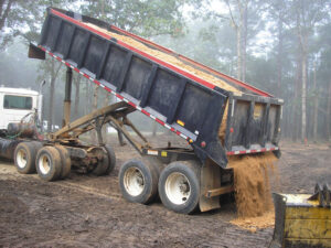 A dump truck unloading dirt or sand at a construction site by Daniel Dean Land Clearing & Dirt Work in Houston, TX.